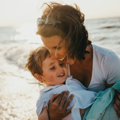 mom holding son, both laughing, at a st. simons beach