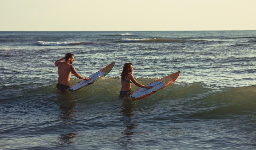 A man and a woman holding surfboards in the ocean in Costa Rica