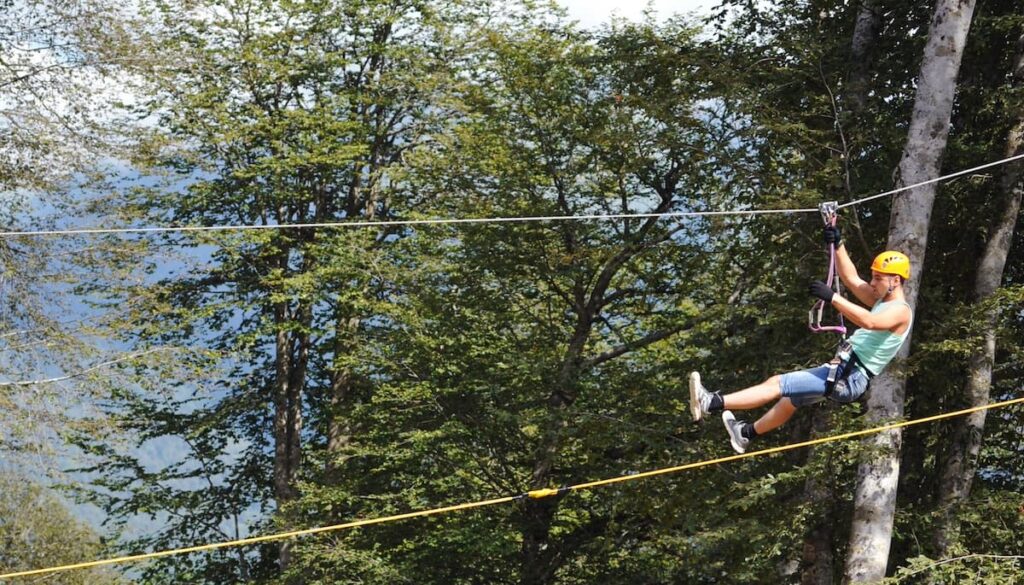 Man zip-lining through trees in a forest wearing a yellow helmet in Costa Rica