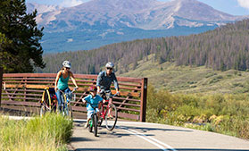 A family bikes on the trail between Breckenridge and Frisco in Summit County, Colorado