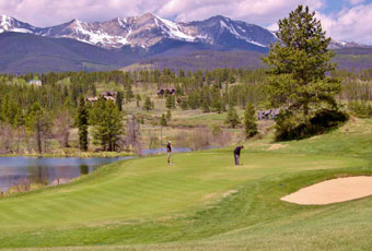 Breckenridge ski resort rises imperiously in the background as a golfer lines up his putt.
