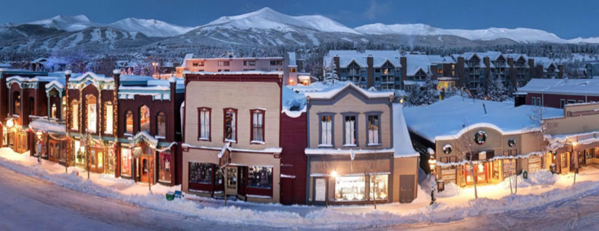 Main Street Breckenridge, illuminated by lights and store fronts reflect the 1880's charm of yesteryear while the ski resort accents the background.