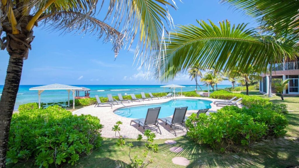 Grand Cayman vacation rental with pool overlooking the ocean surrounded by green palm trees