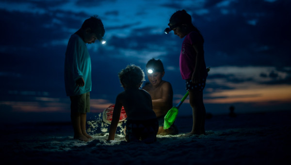 kids with flashlights exploring on the beach at night