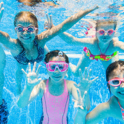 five kids swimming underwater in a pool