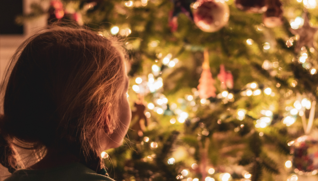 little girl looking at decorated Christmas tree