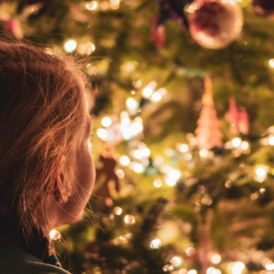 little girl looking at decorated Christmas tree