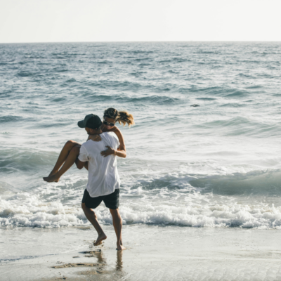 man carrying woman on beach