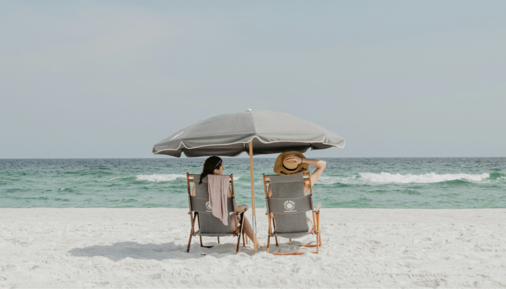 two women under a beach umbrella at the beach