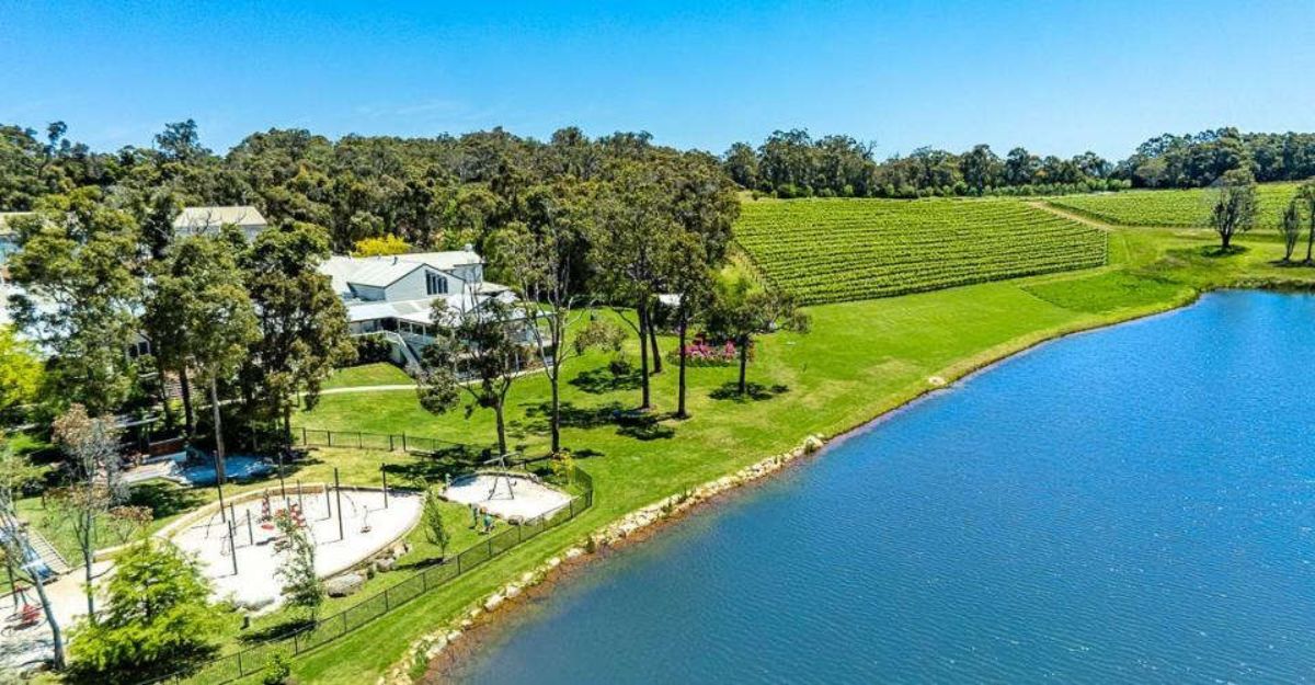 Scenic aerial view of a vineyard estate by a serene lake during winter in Western Australia, showcasing lush greenery and recreational areas, ideal for a peaceful getaway