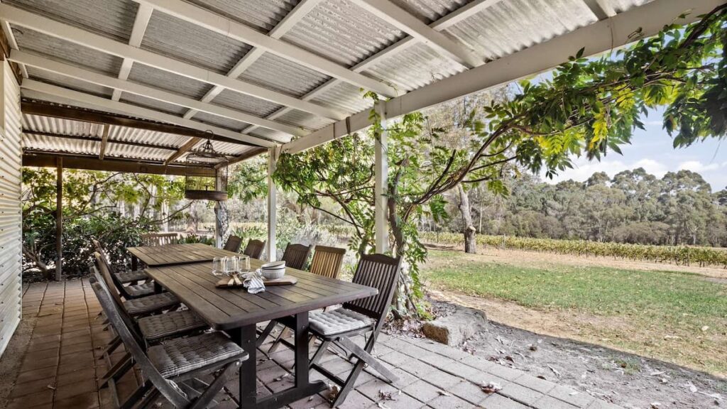 Wisteria Vines Estate's outdoor patio with large veranda and dining table surrounded by lush gardens