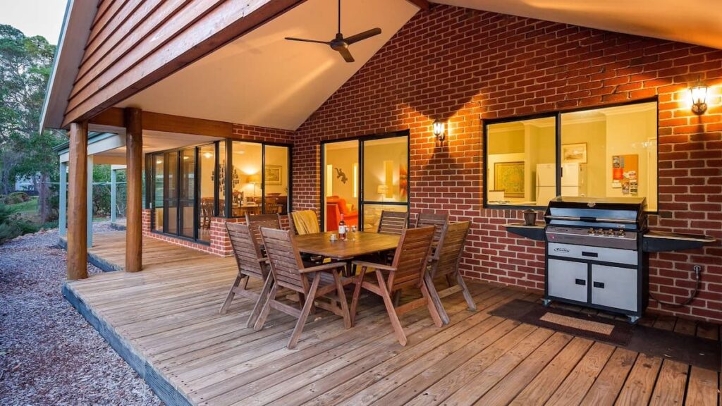 Vaila's outdoor wooden patio with dining set and BBQ looking out onto spacious gardens