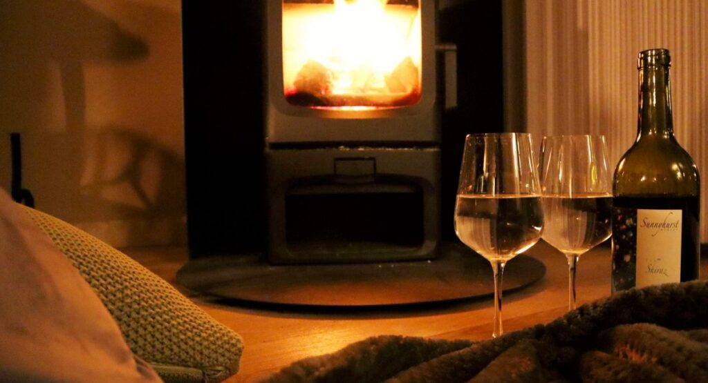 A bottle of wine with glasses in front of a cozy fireplace in a romantic accommodation in Western Australia