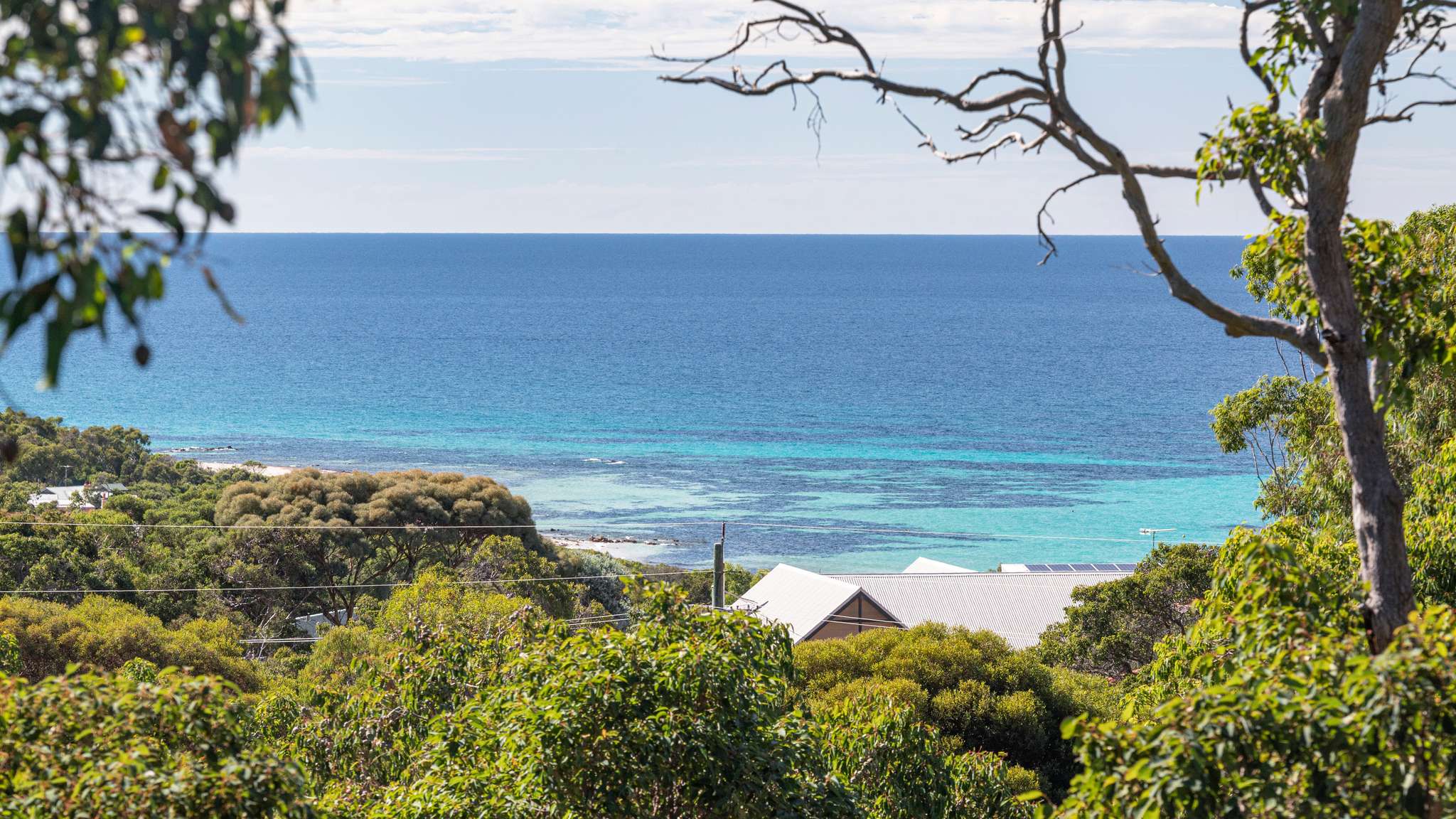 View of the Indian Ocean and turquoise blue waters through trees and bushes in Eagle Bay, WA