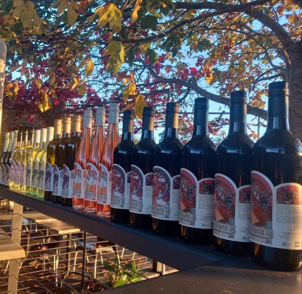 Row of different wine bottles with leaves in background at the Hidden River Estate in Pemberton