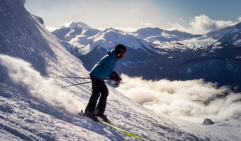 Woman skiing down Whistler mountain with snow-covered mountains in the background