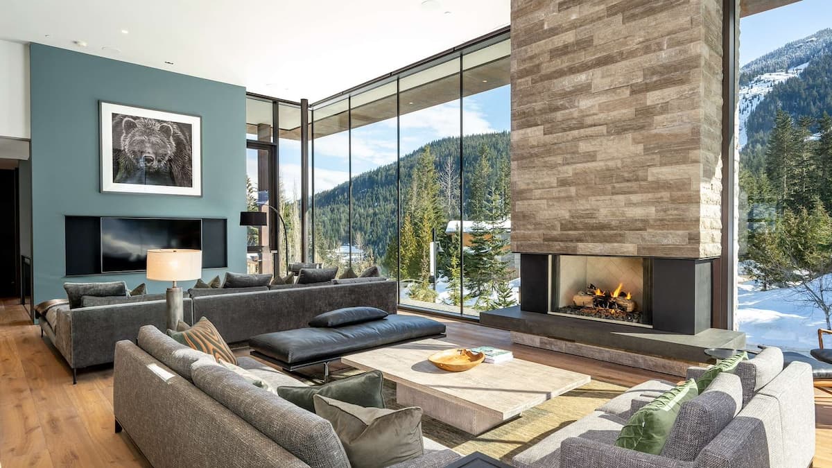 Large open plan living area with floor to ceiling windows and a floor to ceiling stone fireplace