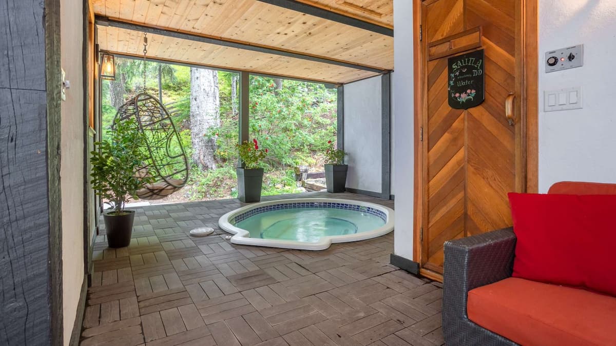 Private hot tub and sauna with an egg hanging chair overlooking green garden