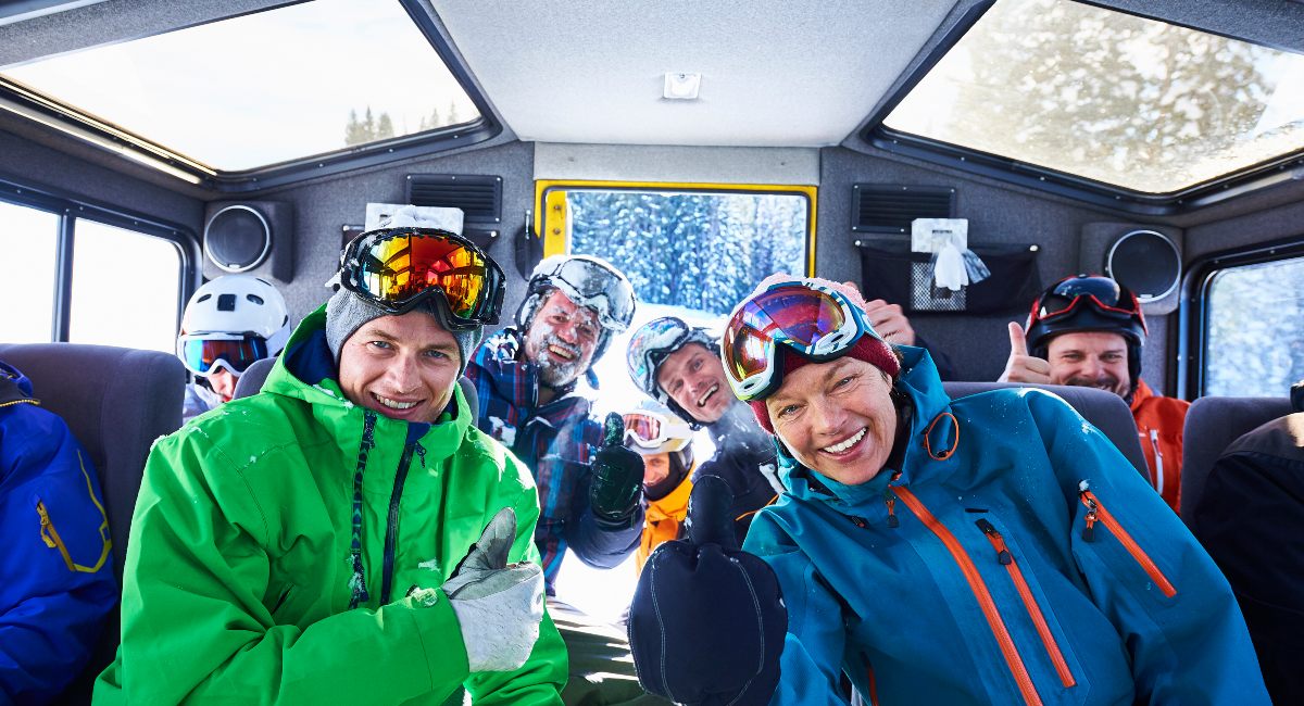 Group of adventure seekers in colourful gear posing in a vehicle during a snowshoeing adventure in Whistler.