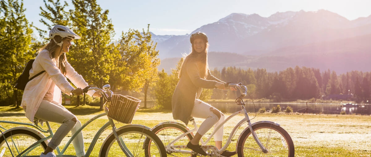 Friends bike riding in Whistler. Lakes and mountains in the background