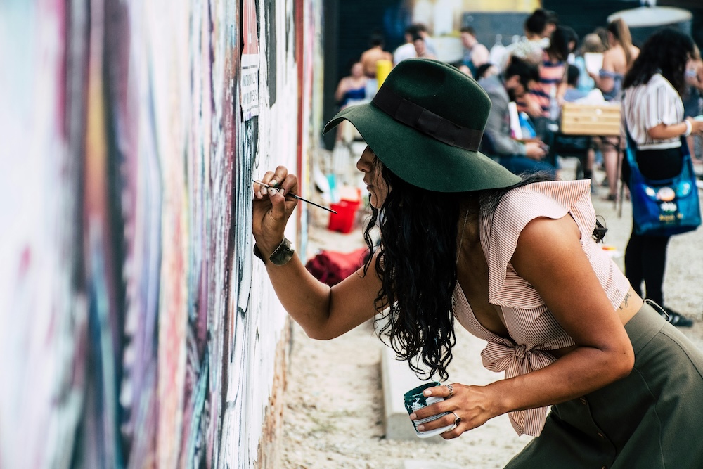 Artist painting a mural on an adobe wall