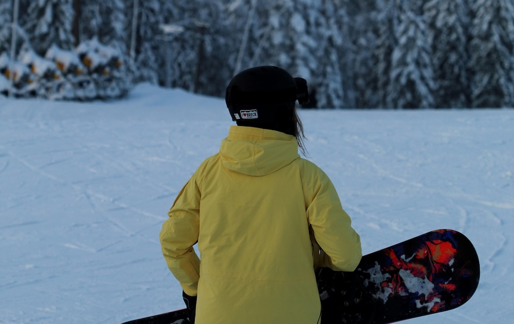 Young skier holding snowboard