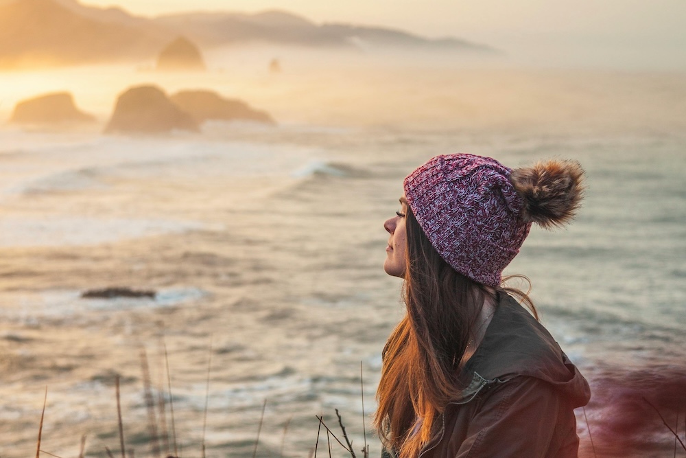 woman sitting on cliff overlooking Oregon coast