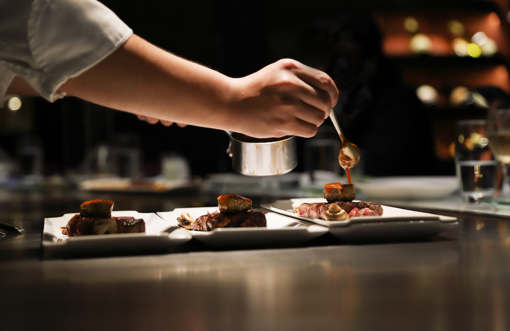 chef plating food in front of guests.