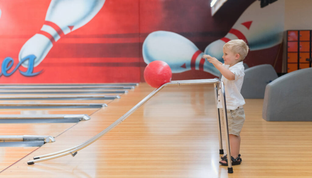young boy at bowling alley throwing bowling ball
