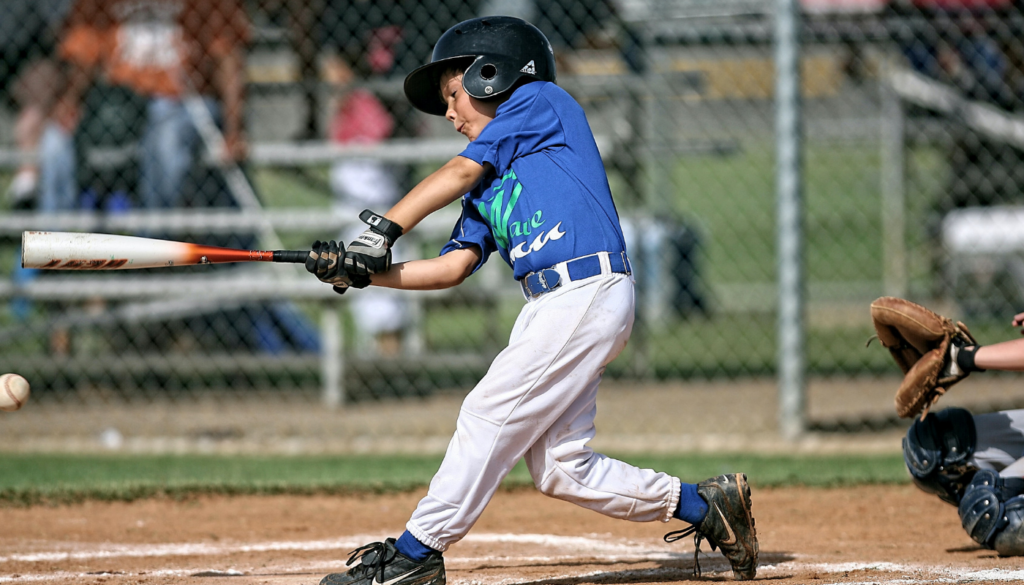 young boy in uniform swinging a baseball bat at a game
