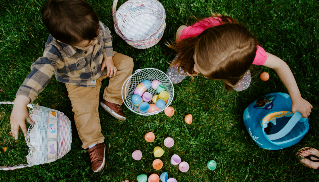 two young children sitting on the grass with easter baskets and candy