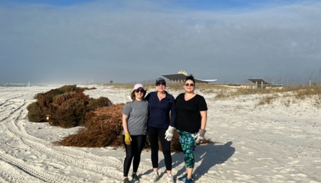 three kaiser vacation rentals employees at the beach with Christmas trees in the background representing community outreach