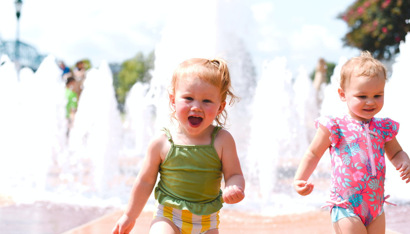 two small children running at a water pad area at OWA