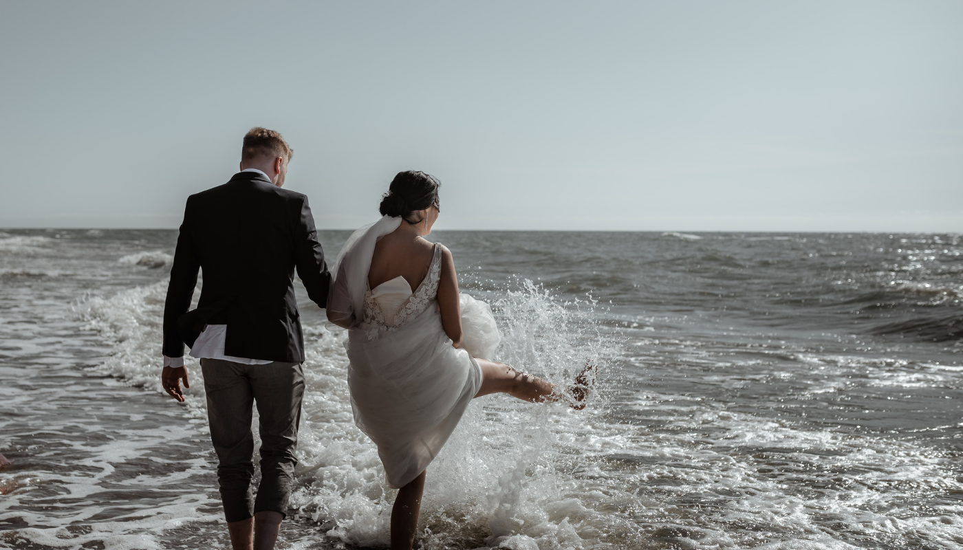 bride and groom walking on beach shoreline