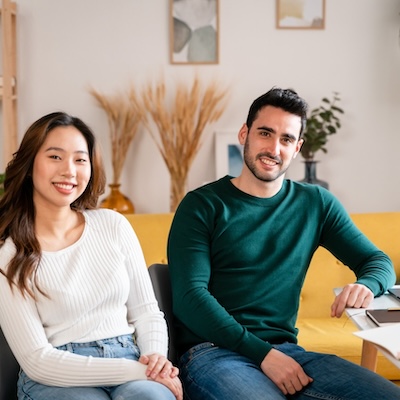Positive young man and woman in casual clothes sitting at table with laptop and taking notes in notebook while learning in Dynamic Rental Pricing for Market Stability