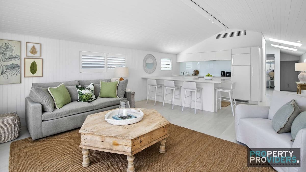 Spacious white kitchen and living area in the granny flat with grey couches and wooden coffee table