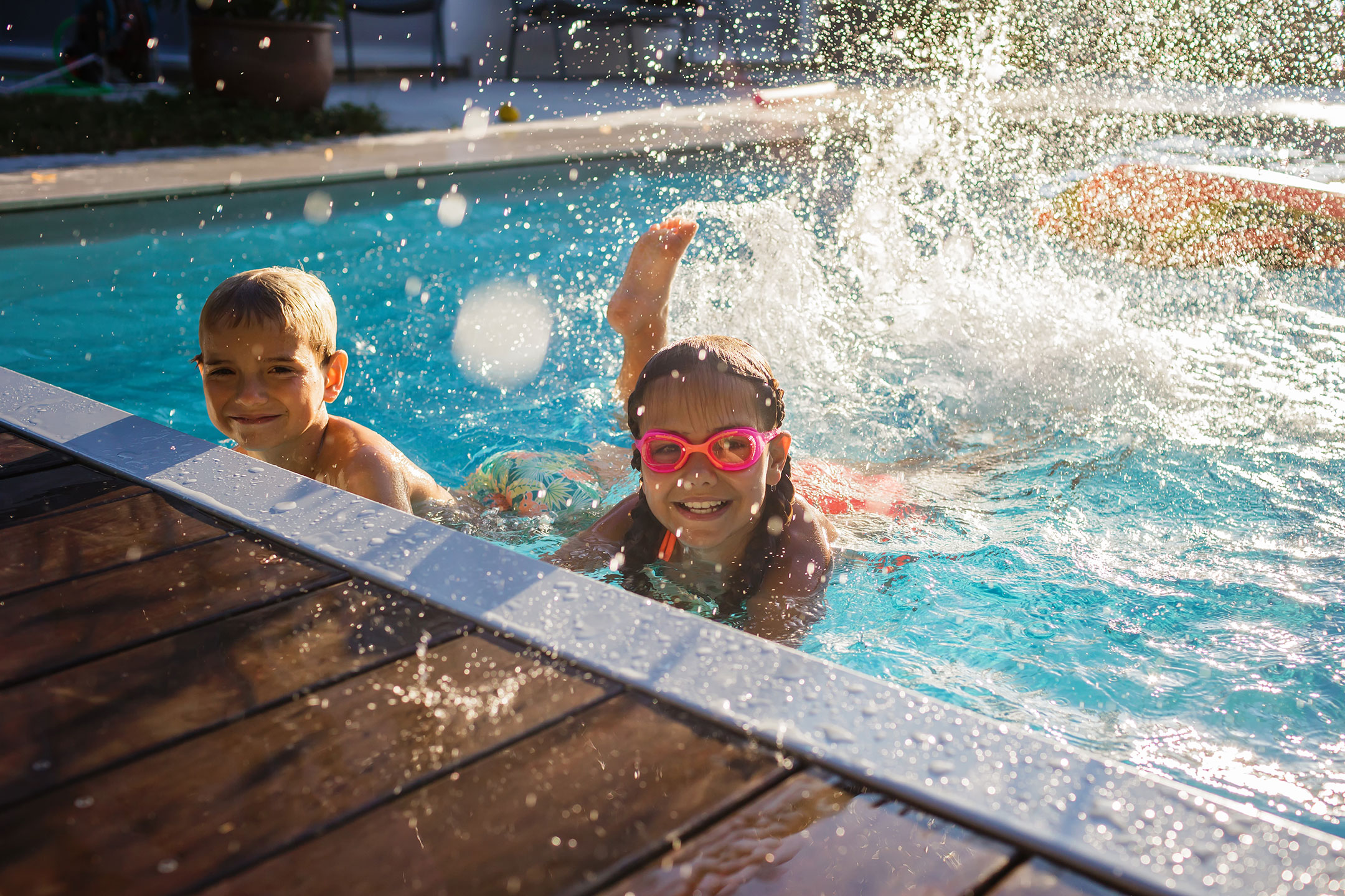 Two happy children playing in a swimming pool on a sunny day during school holidays in Sydney