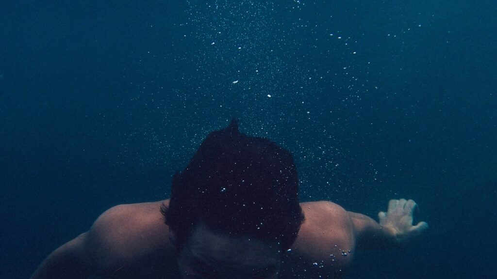 Man swimming underwater, symbolizing reduced visibility and impact on search rankings from cancelling short-term rental bookings.