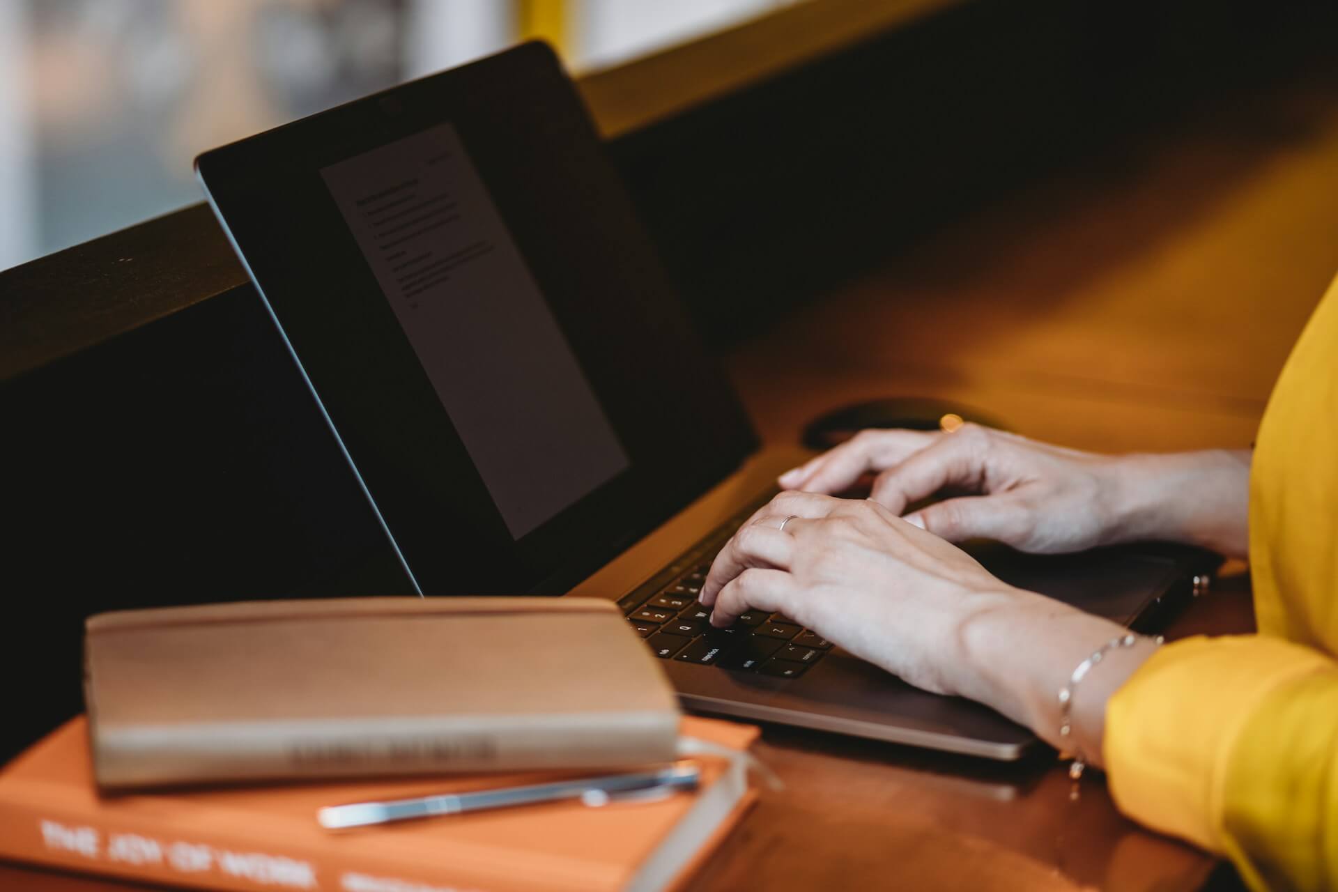 Hands typing on a laptop with books nearby, representing landlords researching NSW rental laws.