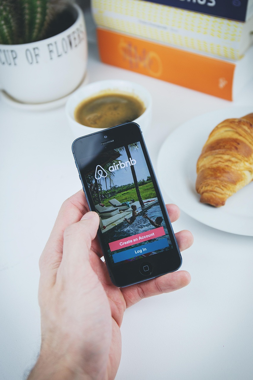 airbnb, app, apple, book, coffee, croissant, hand, holding, ios, iphone, mobile, phone, table, white, airbnb, airbnb, airbnb, airbnb, airbnb-2941142.jpg