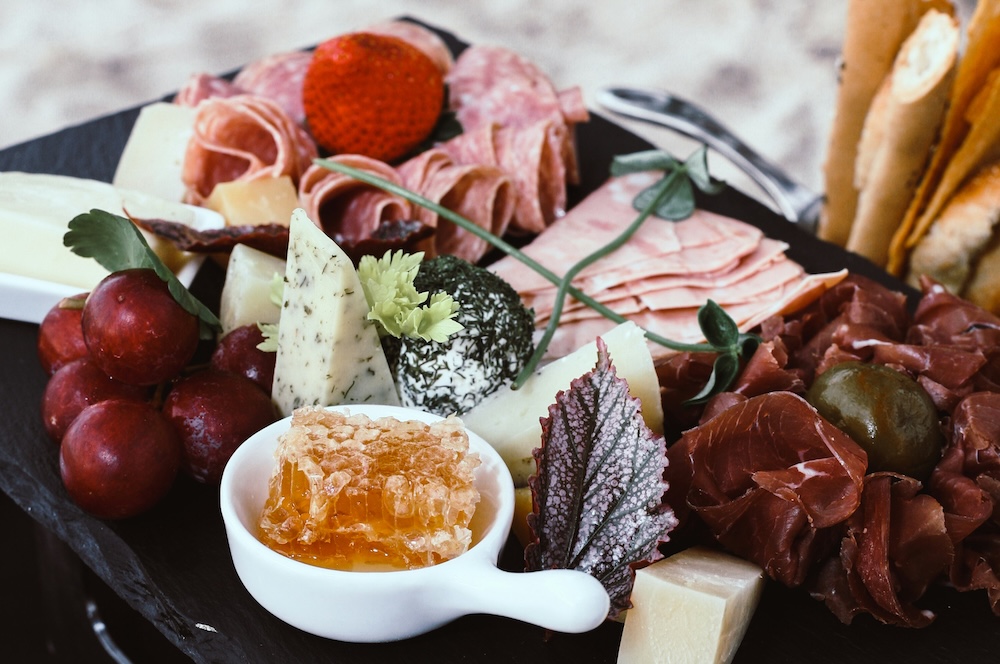Charcuterie board of meats, fruits, and cheeses.