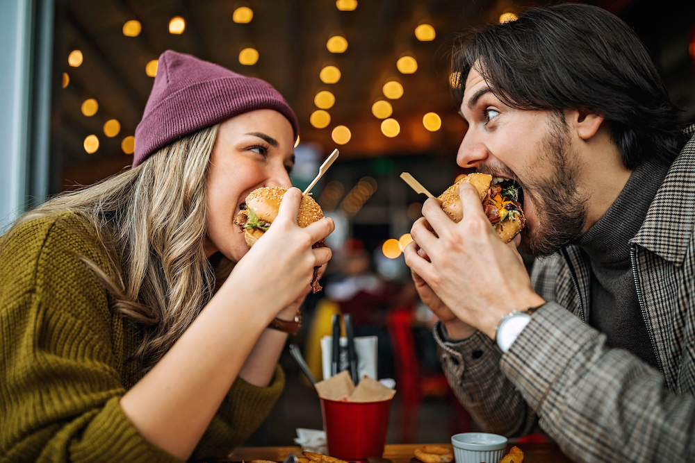 man and woman eating burgers at a restaurant