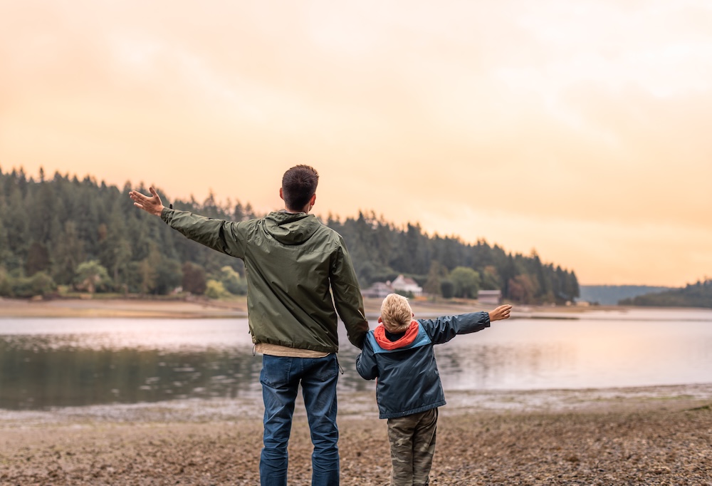 Father and son outside in nature in the pacific northwest near a calm river