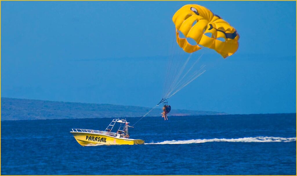 Yellow boat pulling two people parasailing on Maui