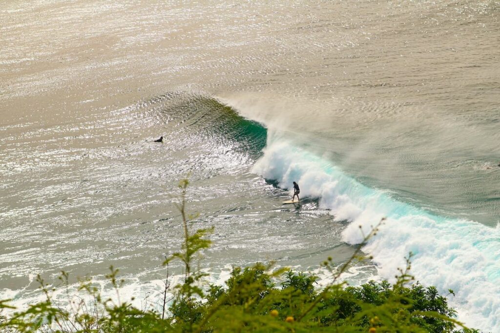 Surfer riding a wave on Maui which is a budget-friendly activity