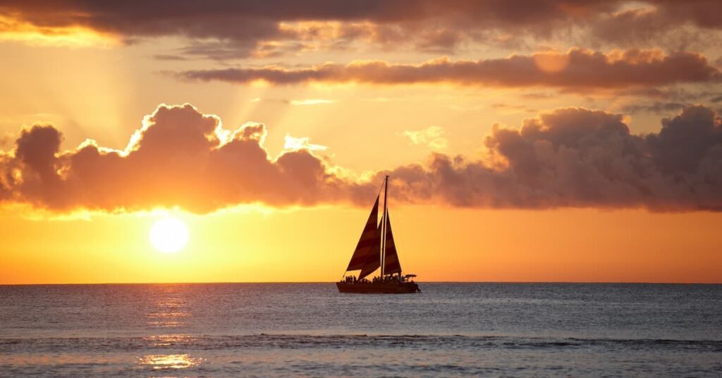 Large sailboat in the ocean at sunset in Maui where you can go on a sunset cruise in Maui in February