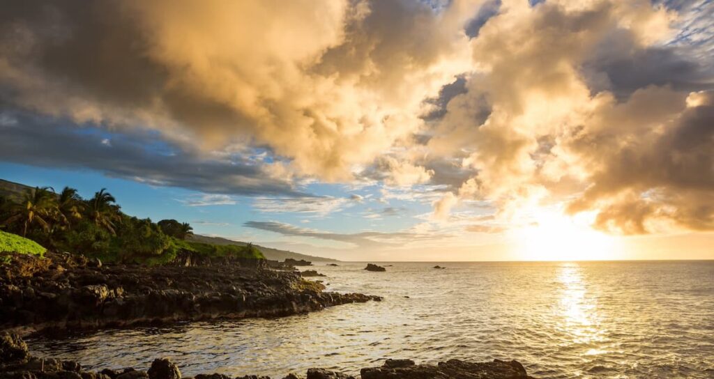 Sun setting over the water at a beach on Maui with clouds in the sky