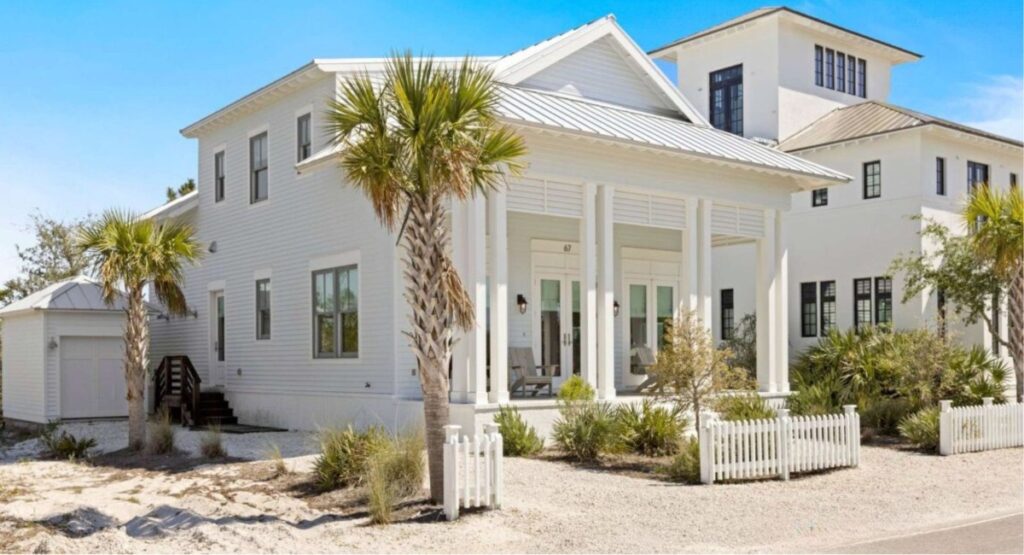 A white multi-storey vacation rental with palm trees and sand around it in Orange Beach, Alabama