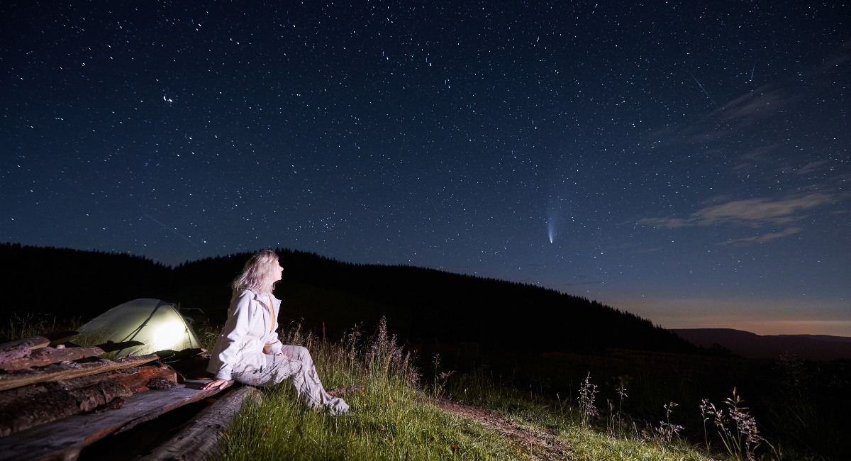  Young woman sitting in mountains with starry sky