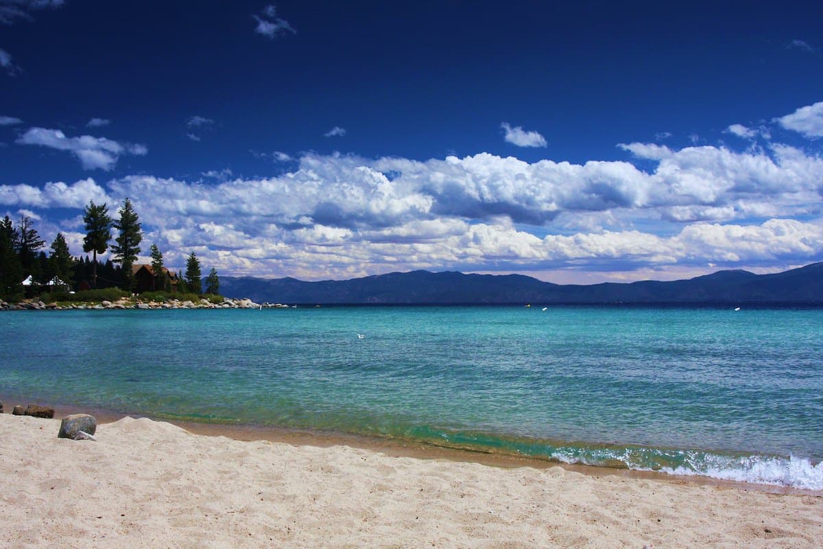 Sandy shoreline at Meeks Bay with blue waters and mountains in background